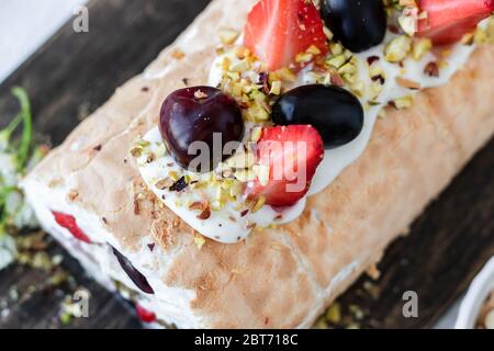 Meringa con frutti di pralina al pistacchio fresco e panna montata e crema di formaggio a cagliata. Dessert estivo Foto Stock