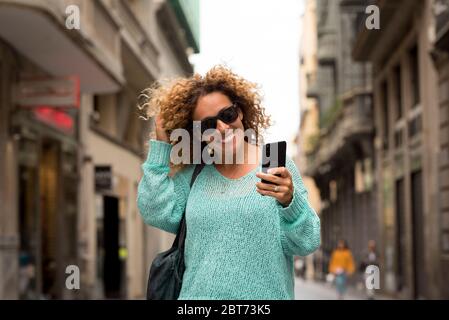 Ritratto f allegro adulto bella donna fare telefono con la tecnologia moderna cellulare a piedi per la strada in città - concetto di outdoor urbano p Foto Stock