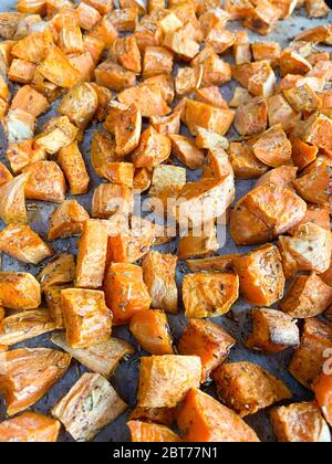 Pezzi di patate dolci all'arancia appena sfornati con condimento al rosmarino Foto Stock