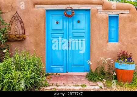 New Mexico tradizionale architettura colorata con porte dipinte di colore blu turchese e decorazioni in stile Ristras nel giardino d'ingresso Foto Stock