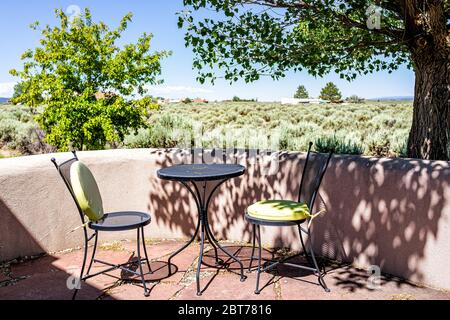 Cortile patio giardino con sedie e tavolo nella valle di Ranchos de Taos e verde paesaggio in estate soleggiato giorno e nessuno Foto Stock