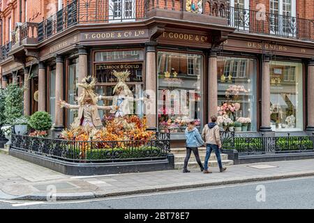 Due persone che camminano accanto alla mostra di caverchi fuori Thomas Goode & Co, una cina, argenteria e vetro Mayfair, Londra Foto Stock