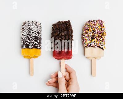 Pop-sicle assortite immerse in cioccolato, cocco, spruzzi e patatine di cioccolato Foto Stock