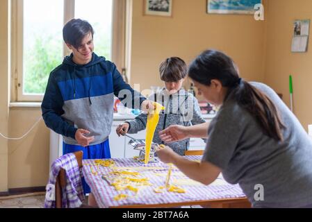 madre con bambini prepara tagliatelle fatte in casa Foto Stock