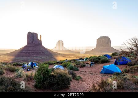 Monument Valley, USA - 13 agosto 2019: Persone al campeggio vista con tende e famosi Mittens canyon butte durante il paesaggio chiaro raggi di alba Foto Stock
