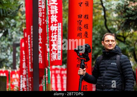 Tokyo, Giappone - 31 marzo 2019: Il santuario di HIE torii porta con l'uomo fotografo che filma gimbal e fotocamera nel quartiere di Akasaka reparto Foto Stock