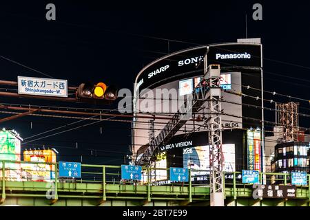 Shinjuku, Giappone - 3 aprile 2019: Cartello commerciale notturno del centro di Tokyo con sfondo nero e tracce della stazione ferroviaria con il segno A. Foto Stock