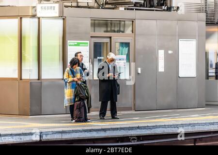 Utsunomiya, Giappone - 5 aprile 2019: Piattaforma della stazione ferroviaria con la gente d'affari che aspetta in fila per il treno ad alta velocità Shinkansen alla sera con il segno in it Foto Stock