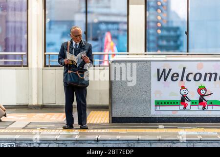 Utsunomiya, Giappone - 5 aprile 2019: Piattaforma della stazione ferroviaria con l'uomo d'affari gente che legge la rivista di macchina fotografica in attesa di Shinkansen bullet train a pari Foto Stock