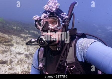 23 MAGGIO 2020, CRYSTAL RIVER, FL: Un anziano SUBACQUEO accende la fotocamera per catturare un ritratto subacqueo nella Primavera di Hunters. Foto Stock