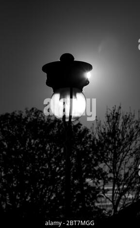 Vecchia lampada a lampione sul Mound illuminata dalla luce del sole dalla stazione di Waverley Edimburgo. Scatti in bianco e nero di grande effetto. Foto Stock