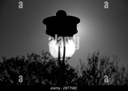 Vecchia lampada a lampione sul Mound illuminata dalla luce del sole dalla stazione di Waverley Edimburgo. Scatti in bianco e nero di grande effetto. Foto Stock