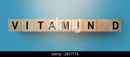 Parola di vitamina D fatta da cubi di legno con lettere sulla tavola blu cielo. Concetto di assistenza sanitaria Foto Stock