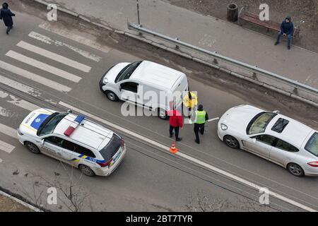 KIEV, UCRAINA - 02 FEBBRAIO 2020: Una macchina della polizia arriva a un incidente stradale di attraversamento pedonale con i conducenti non identificati in piedi fuori t. Foto Stock