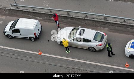 KIEV, UCRAINA - 02 FEBBRAIO 2020: Una macchina della polizia arriva a un incidente stradale di attraversamento pedonale con i conducenti non identificati in piedi fuori t. Foto Stock