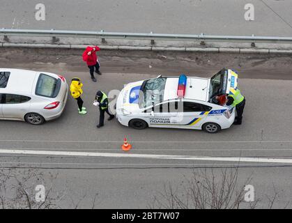 KIEV, UCRAINA - 02 FEBBRAIO 2020: Una pattuglia di polizia arriva a un incidente stradale con i conducenti non identificati in piedi fuori del veicolo. Vista da Foto Stock