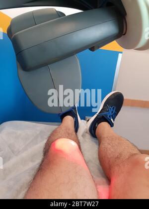 Laser terapia. Terapia fisica con un laser per trattare un ginocchio ferito Foto Stock