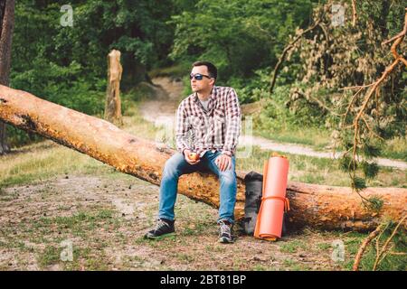 Ritratto giovane escursionista maschile mangiare mela. Turista alla foresta, sosta per riposare e mangiare mela. Uomo in forma mangiare una mela all'aperto nei boschi. Uomo caucasico Foto Stock