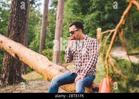 Ritratto giovane escursionista maschile mangiare mela. Turista alla foresta, sosta per riposare e mangiare mela. Uomo in forma mangiare una mela all'aperto nei boschi. Uomo caucasico Foto Stock