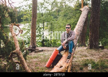 Ritratto giovane escursionista maschile mangiare mela. Turista alla foresta, sosta per riposare e mangiare mela. Uomo in forma mangiare una mela all'aperto nei boschi. Uomo caucasico Foto Stock