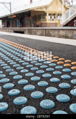 Gli urti vescicolati, i punti sollevati o le cupole troncate fungono da marcatori di avvertimento rilevabili per persone ipovedenti su una piattaforma della stazione ferroviaria di Sydney Foto Stock