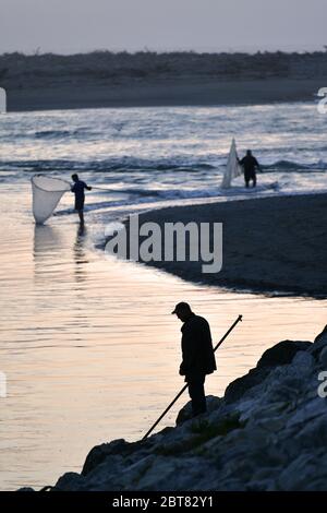 HOKITIKA, NUOVA ZELANDA, 24 OTTOBRE 2019: Un uomo usa una rete a paletta al tramonto per catturare il whitebait al fiume Hokitika sulla costa occidentale del sud Foto Stock
