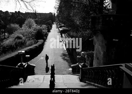 Uomo solitario che cammina verso la scalinata fuori da un deserto Princes Street Gardens Edimburgo durante il blocco 2020. Scatti in bianco e nero di grande effetto. Foto Stock