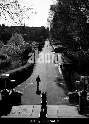 Uomo solitario che cammina verso la scalinata fuori da un deserto Princes Street Gardens Edimburgo durante il blocco 2020. Scatti in bianco e nero di grande effetto. Foto Stock