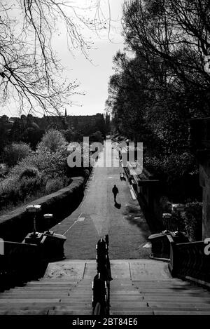 Uomo solitario che cammina verso la scalinata fuori da un deserto Princes Street Gardens Edimburgo durante il blocco 2020. Scatti in bianco e nero di grande effetto. Foto Stock