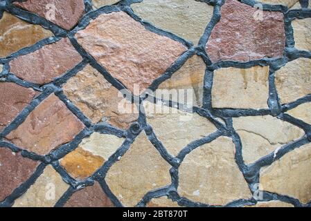 Struttura di pavimentazione in blocchi di pietra di colore naturale. Muro di pietra con cuciture nere. Sfondo dell'edificio Foto Stock