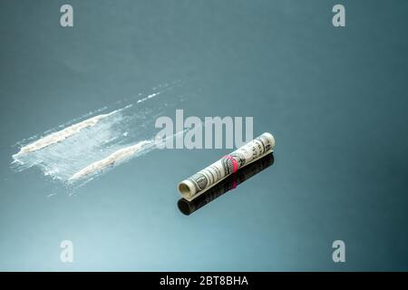 Polvere di cocaina in linee e un dollaro di legge. Strisce narcotiche su sfondo nero Foto Stock