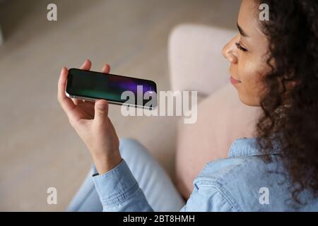 Donna africana che tiene il telefono cellulare utilizzando l'assistente di riconoscimento vocale. Foto Stock