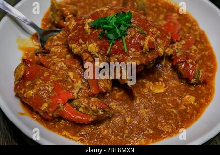 Primo piano di piccante Crab Chili, piatto caratteristico della cucina Singaporiana, servito su un piatto in un ristorante a Singapore Foto Stock
