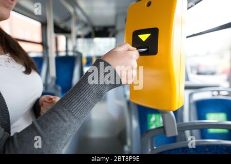 La mano della giovane donna inserisce il biglietto dell'autobus nel concetto di convalida, convalida e ticking, trasporto pubblico Foto Stock