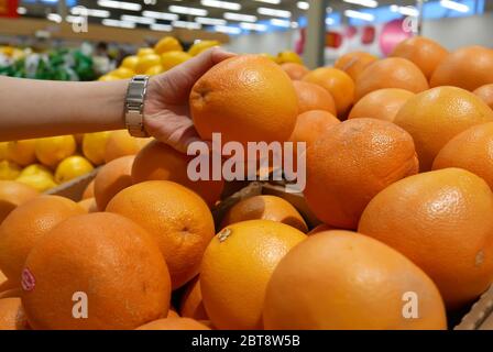 Movimento della mano della donna che raccoglie il pompelmo all'interno del superstore Foto Stock