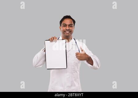 Appunti di mantenimento medico che mostrano Thumb Up isolato. Gli appunti vuoti del medico dell'uomo indiano nelle mani. Medico Foto Stock