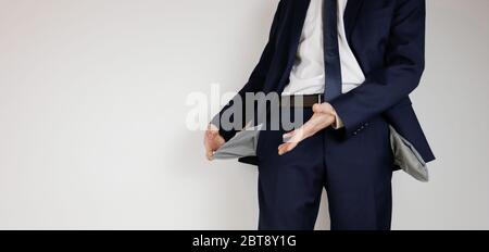 Un uomo in un vestito da lavoro ha girato le sue tasche dentro fuori. Crisi finanziaria. Fallimento nel commercio. Un imprenditore senza soldi. Foto Stock