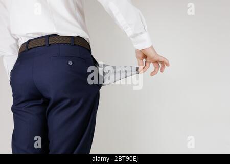 Un uomo in un vestito da lavoro ha girato le sue tasche dentro fuori. Crisi finanziaria. Fallimento nel commercio. Un imprenditore senza soldi. Foto Stock