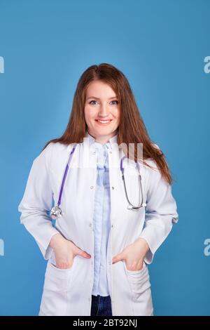 Medico femminile amichevole che tiene le mani in tasche di uniforme Foto Stock