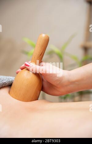 Donna che ha massaggio di maderoterapia posteriore con tazza svedese di legno Foto Stock