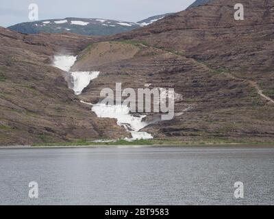 Vista lago e cascata di Svartisen vicino al ghiacciaio europeo Svartisen nella contea di Nordland in Norvegia, cielo nuvoloso nel 2019 freddo giorno estivo il mese di luglio. Foto Stock