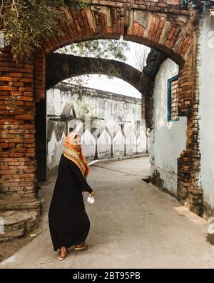 Murshidabad, Bengala Occidentale/India - Gennaio 15 2018: Una donna cammina attraverso vecchi archi sbriciolati sulle strade di Murshidabad. Foto Stock