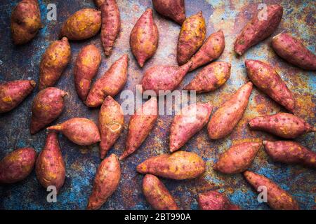 vista dall'alto sulle patate dolci rosse, esposizione di cibi crudi su sfondo metallico grunge Foto Stock