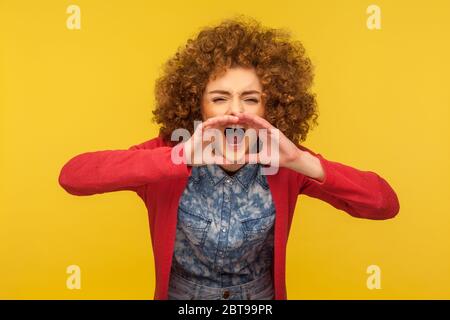 Ritratto di donna stressata con capelli ricci in abito casual gridando forte in mani a forma di megafono, urlando per aiuto, annunciando m importante Foto Stock