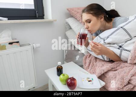 Tè caldo con erbe. Una giovane ragazza adolescente si trova malata dal suo letto. Freddo acuto. Foto Stock