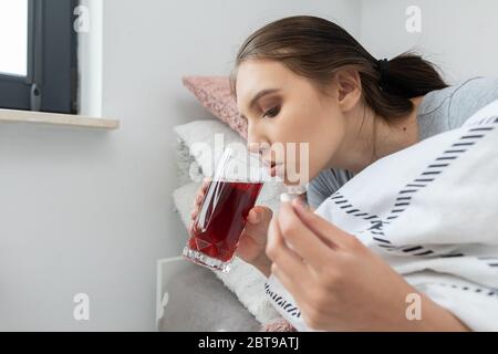 Tè caldo con erbe. Una giovane ragazza adolescente si trova malata dal suo letto. Freddo acuto. Foto Stock