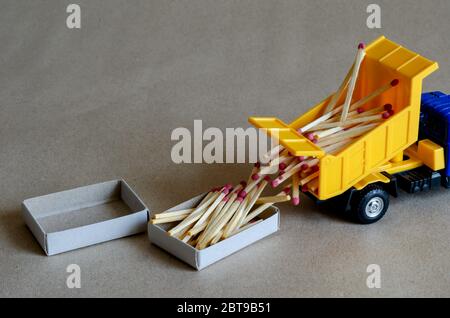 Un camion giocattolo giallo rovesciamento versamenti fiammiferi. Un camion giocattolo scarica un corpo pieno di fiammiferi di legno. Ambiente creativo industriale. Argomenti logistici. Selettivo Foto Stock