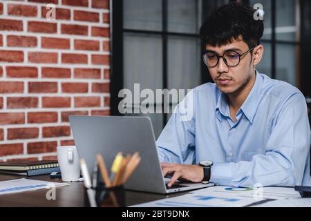 Imprenditore asiatico di Woking con il computer portatile e il foglio di lavoro sulla scrivania in ufficio.workflow digitale business online il concetto di stile di vita Foto Stock
