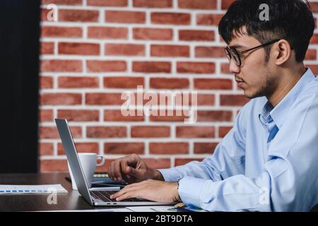 Imprenditore asiatico di Woking con il computer portatile e il foglio di lavoro sulla scrivania in ufficio.workflow digitale business online il concetto di stile di vita Foto Stock
