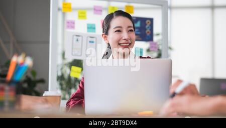 ritratto di una donna asiatica sorridente quando si incontra con lo sviluppatore ux e la designer ui sul design a reticolo dell'interfaccia app mobile sul tavolo riunioni all'indirizzo